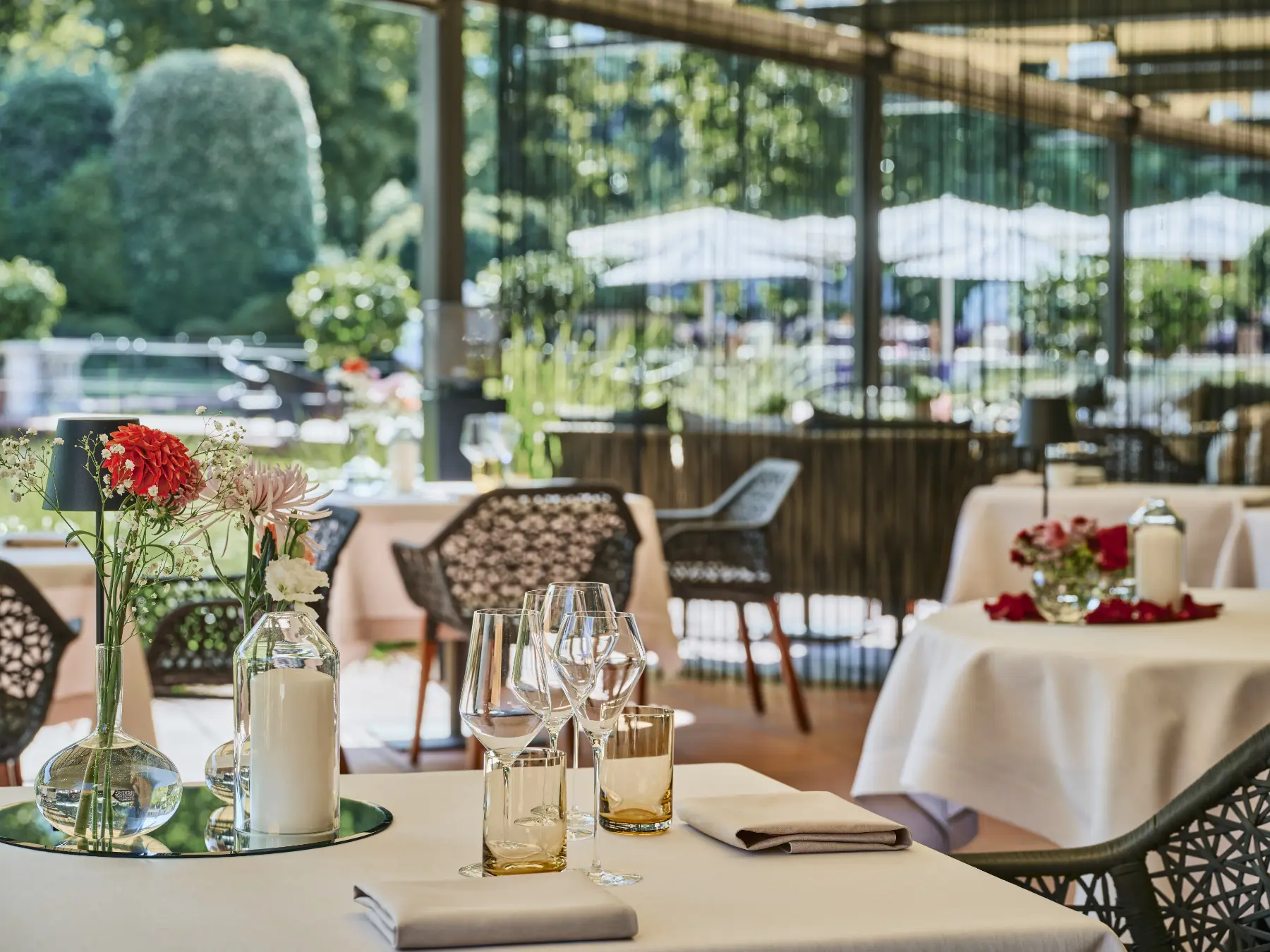 Gedeckte Tische auf der Terrasse des ECCO Ascona mit Blick in den mediterranen Garten des Giardino
